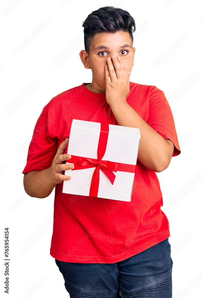 Little boy kid holding gift covering mouth with hand, shocked and afraid for mistake. surprised expression Little boy kid holding gift covering mouth with hand, shocked and afraid for mistake. surprised expression
