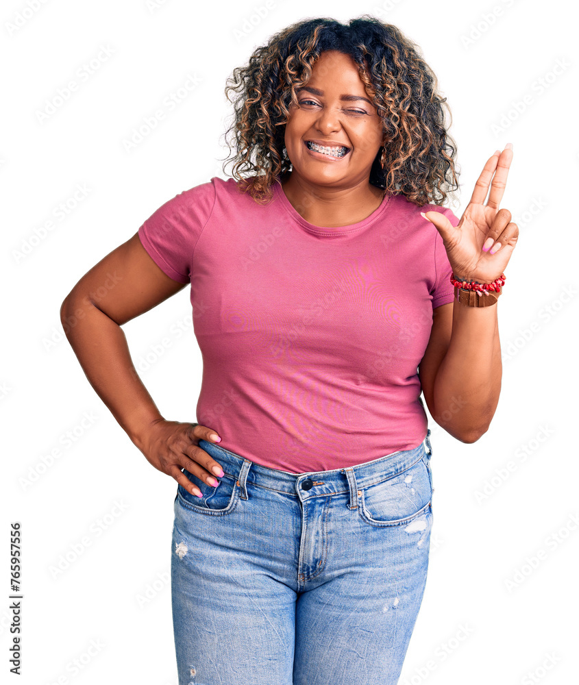 Young african american plus size woman wearing casual clothes smiling with happy face winking at the camera doing victory sign with fingers. number two.