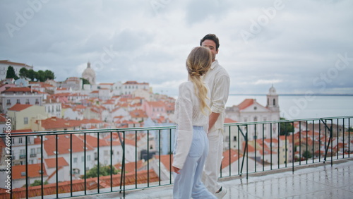 Affectionate pair strolling rooftop admiring city views together. Happy partners