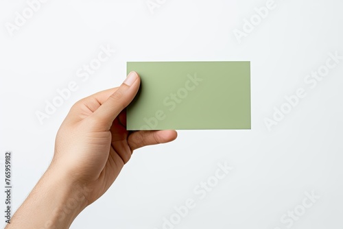 Hand holding a blank green business card on white background