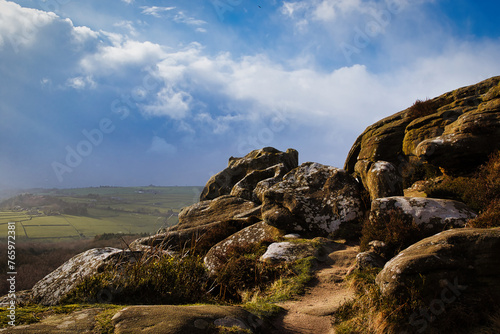 Majestic rocky landscape with sunlit grass under a blue sky with clouds at Brimham Rocks, in North Yorkshire © Vas