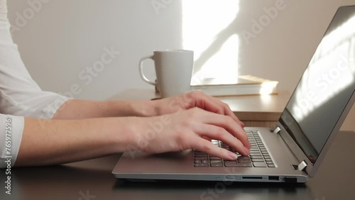 Side view on woman's hands, typing the text on laptop. 