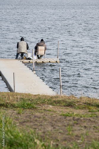 dwóch wędkarzy siedzących na krzesełkach na drewnianym pomoście i łowiących ryby w jeziorze © Andrzej Michaluk