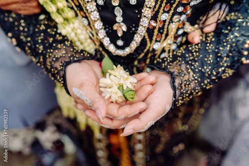 close up of hands of the grom with a bouquet of flowers photo