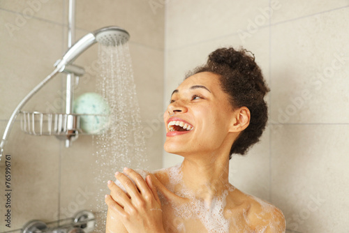 фотографія A woman in the shower, smiling and enjoying the water from the plumbing fixture