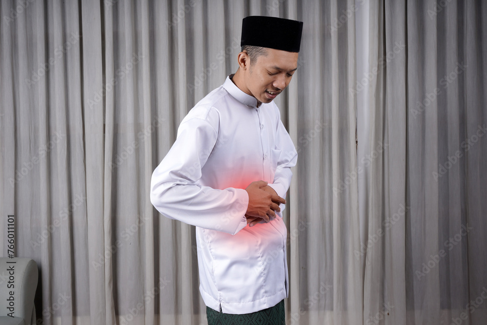 Muslim Asian man touching his stomach with in pain expression. Diseases of the gastrointestinal tract that often cause abdominal pain, such as appendicitis, enteritis