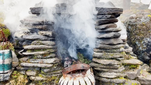 Holy puja ceremony fireplace. Smoke flying up and covering Holy buddhist praying multicolored flags with mantras slow motion video in Tuli Kharka village at 4200m on Mera peak climbing route. photo