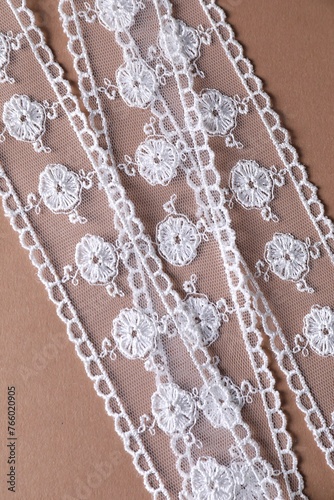 White lace on beige background, top view