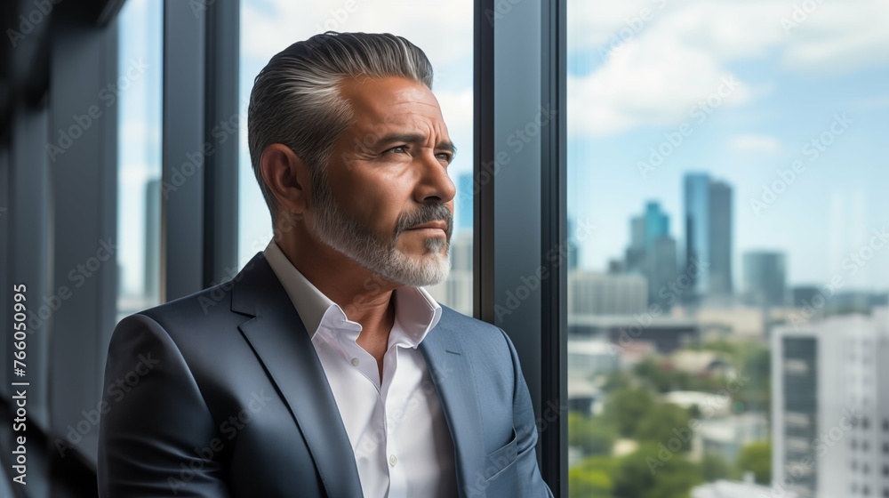 mature optimistic Latino Hispanic businessman executive CEO in corporate modern office thinking contemplating and looking out window skyscraper cityscape daytime with room for text mature optimistic Latino Hispanic businessman executive CEO in corporate modern office thinking contemplating and looking out window skyscraper cityscape daytime with room for text