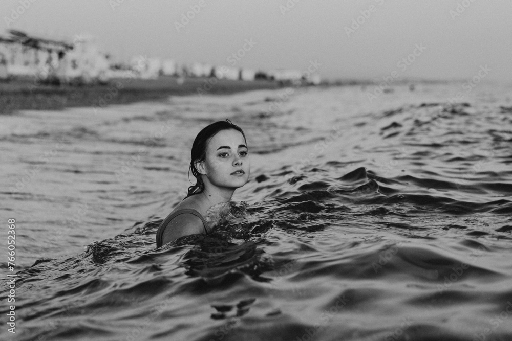 Fototapeta premium Young Woman Swimming in the Calm Ocean Waters at Dusk.