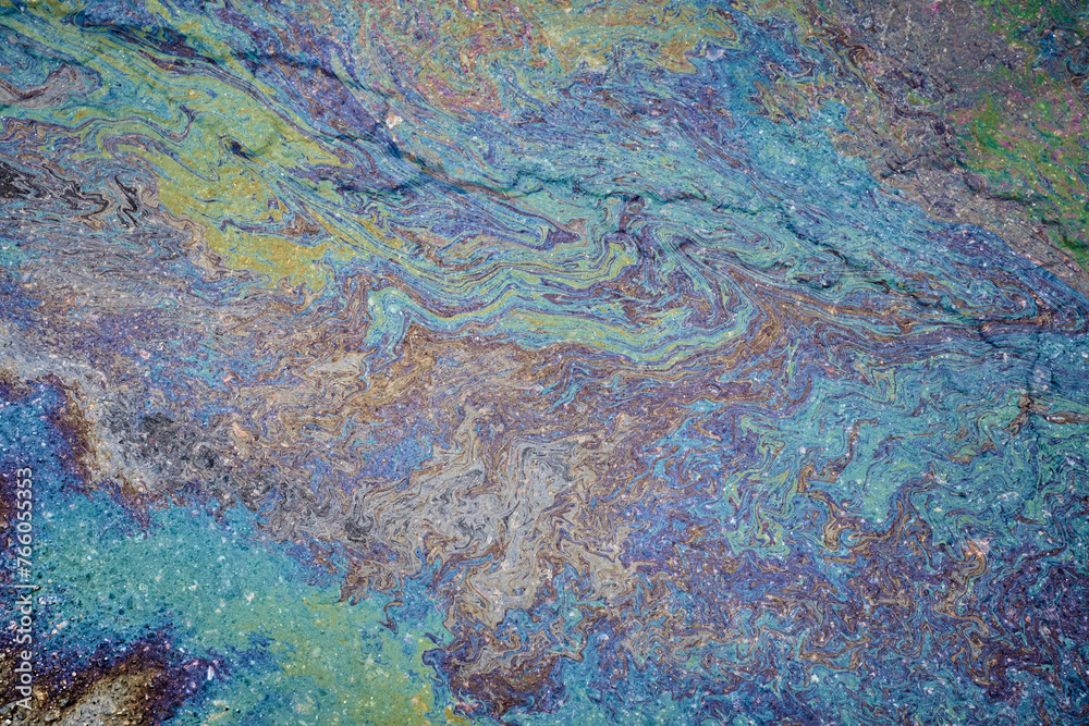 Marble spills on the water from stains of gasoline and oil. Abstract background from motor oil, gas or petrol spilled on asphalt.