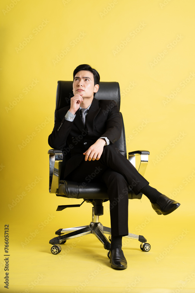 Portrait of Asian male businessman. wearing a suit and posing on a yellow background Portrait of Asian male businessman. wearing a suit and posing on a yellow background