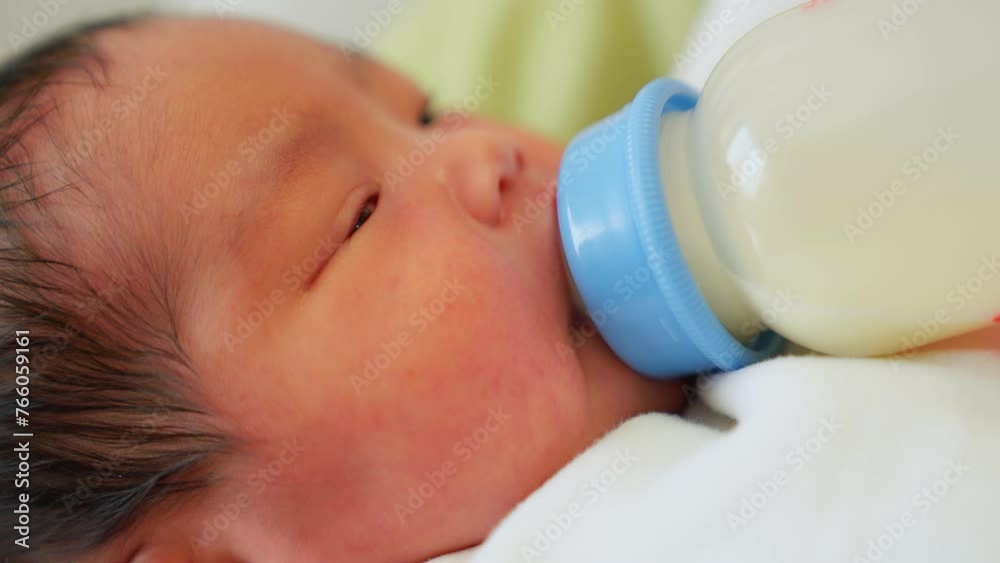 Close up view of mother feeding her baby milk from bottle. Child lying in embrace mom drinking milk powder. Daughter drinks breast milk from pumped milk into bottle. Newborn doesn't enter the breast. Close up view of mother feeding her baby milk from bottle. Child lying in embrace mom drinking milk powder. Daughter drinks breast milk from pumped milk into bottle. Newborn doesn't enter the breast.