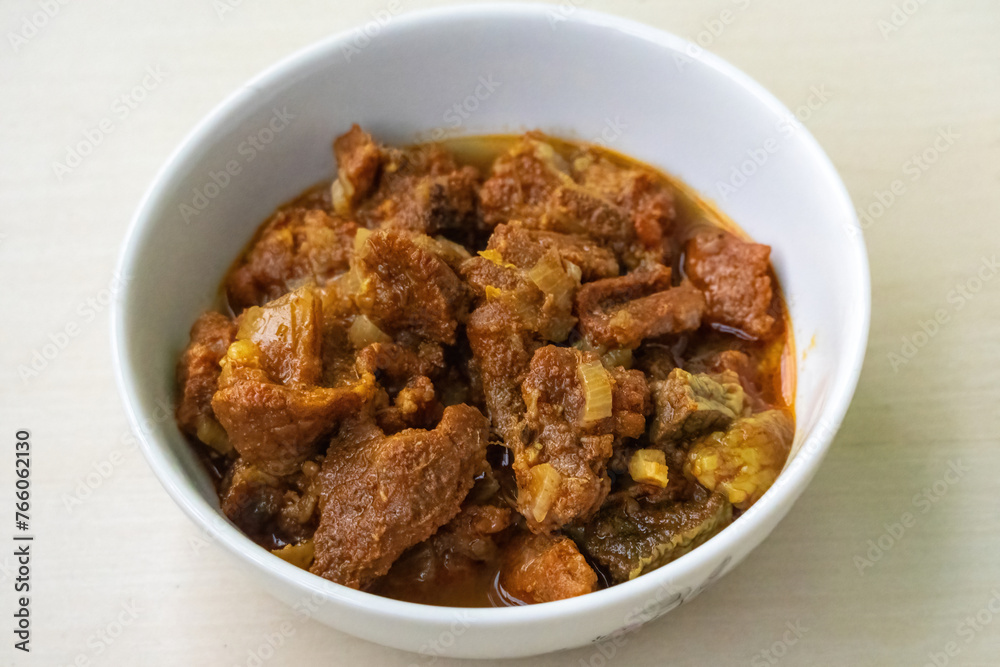 Delicious beef curry in a bowl on wooden background. Beef bhuna is a popular, flavorful, and spicy Bangladeshi dish. It is great food for eating with rice or bread.