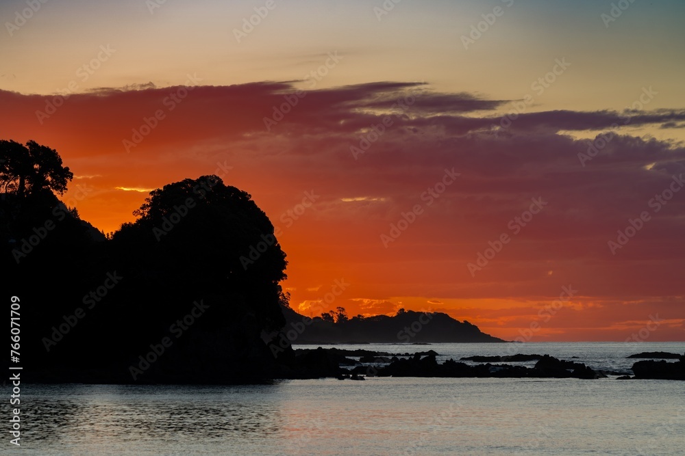 Coastline and red clouds at sunset. Maraehako Bay, Bay of Plenty, New Zealand.