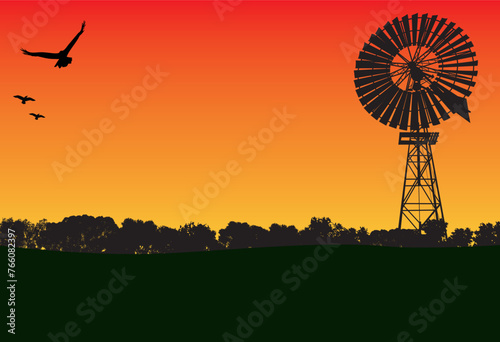 windmill in the sunset and lots of silhouette of trees in the foreground