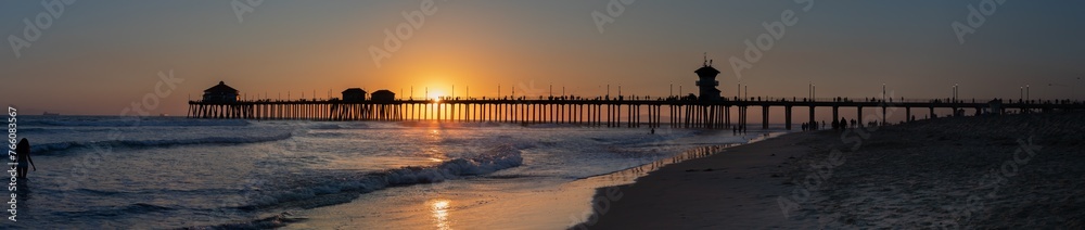 Extra Long Panorama Silhouette of Huntington Beach Pier with Distant People Watching Sunset, March 2024, California, USA