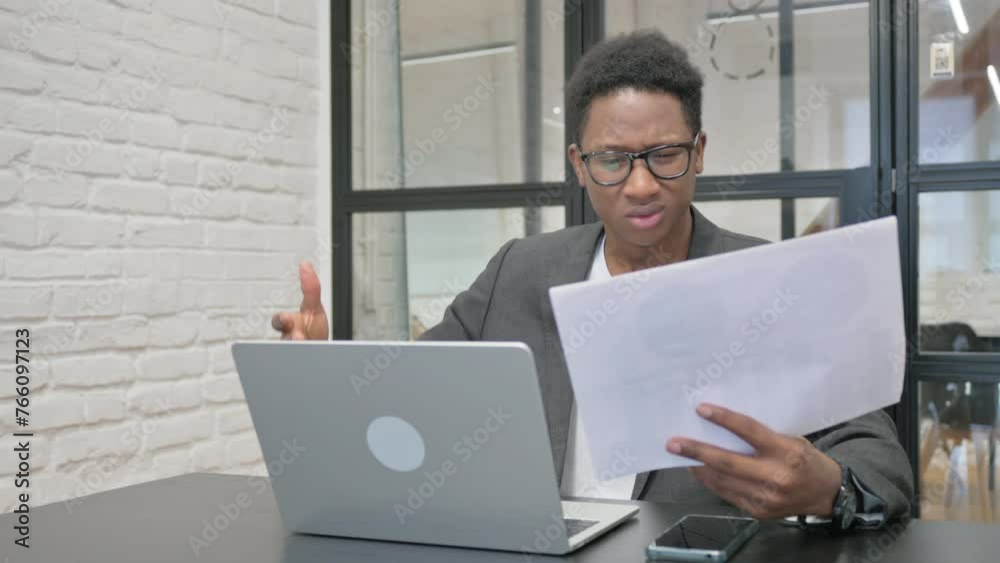 Young African Man Feeling Upset while Reading Contract at Work Young African Man Feeling Upset while Reading Contract at Work