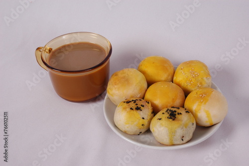 Tau Sar Piah with Sweet green been and Sweet black seeds and salted egg on a white background with a cup of hot milk tea