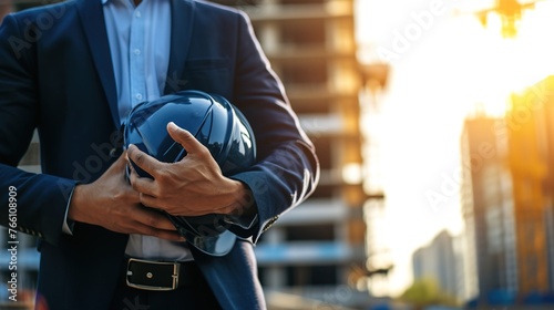 Wearing a hard hat and vest, a construction worker stands on a busy construction site