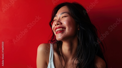 Happy Asian woman grinning and posing against a red background