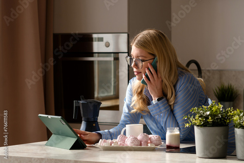 Woman on phone with coffee in kitchen