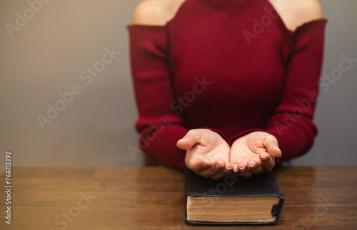 Woman praying for blessings with her hands placed on a bible.