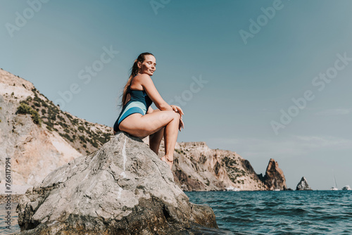 Woman beach vacation photo. A happy tourist in a blue bikini enjoying the scenic view of the sea and volcanic mountains while taking pictures to capture the memories of her travel adventure. © svetograph