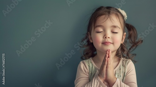 cute little girl praying with folded hands and closed eyes - studio portrait with copyspace