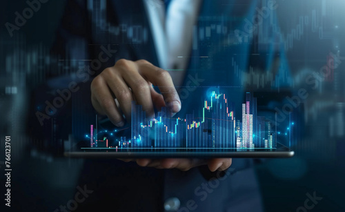 A businessman holding a tablet displaying a digital stock market graph and chart in the style of financial growth on a blue background.  photo