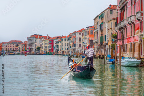 Foto Venetian gondolier punting gondola through grand canal waters of Venice Italy