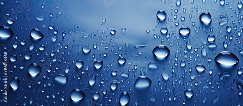 A multitude of liquid droplets rest on an azure surface, resembling a drizzle or dew. The electric blue hue of the water drops adds a touch of vibrancy