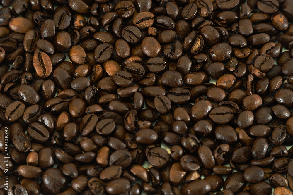 Naklejka premium Close-up of freshly roasted coffee beans piled on a wooden table, creating a rich and aromatic background.