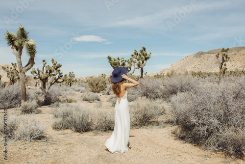Woman in a boho style white dress and hat standing in the Joshua Tree desert 