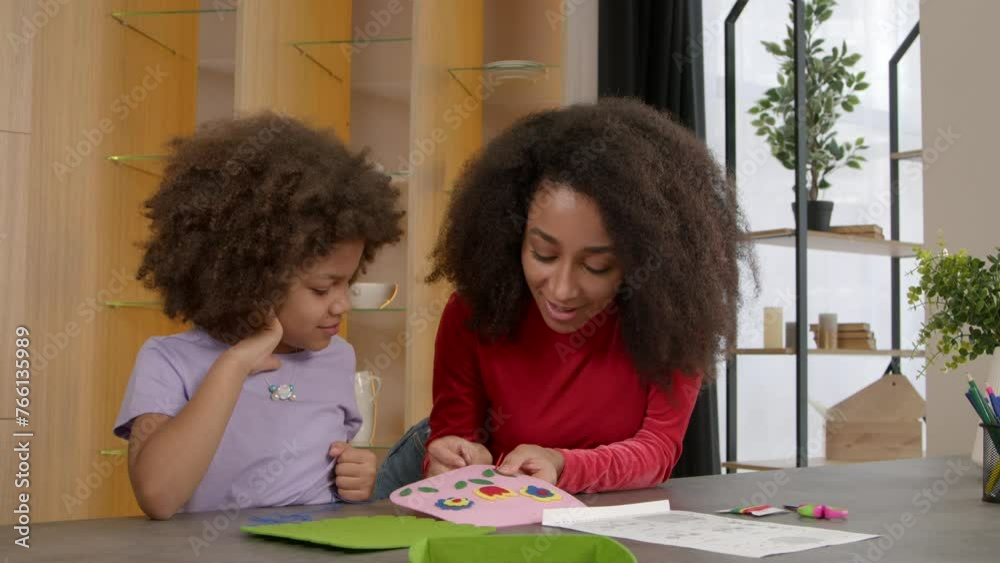 Concentrated engrossed in activity cute preadolescent black daughter with caring attractive mother learning to sew handmade kids handbag using needle and thread , while making DIY accessory . Stock ビデオ | Adobe Stock