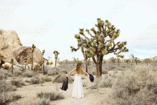 Woman in a boho style white dress and hat standing in the Joshua Tree desert