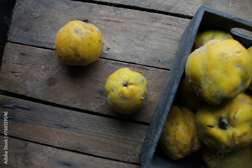 Fresh ripe organic quinces in a box on a wooden table.