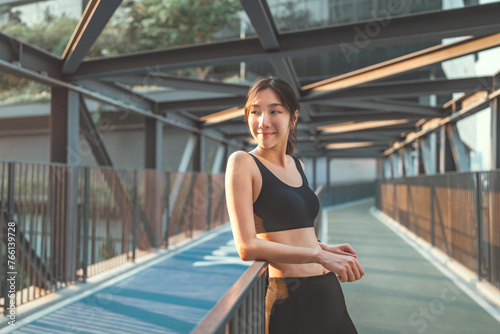 Young happy athletic asian woman in sportswear leaning on banister outdoors sunset after working out, Satisfied fit woman resting after an active fitness training