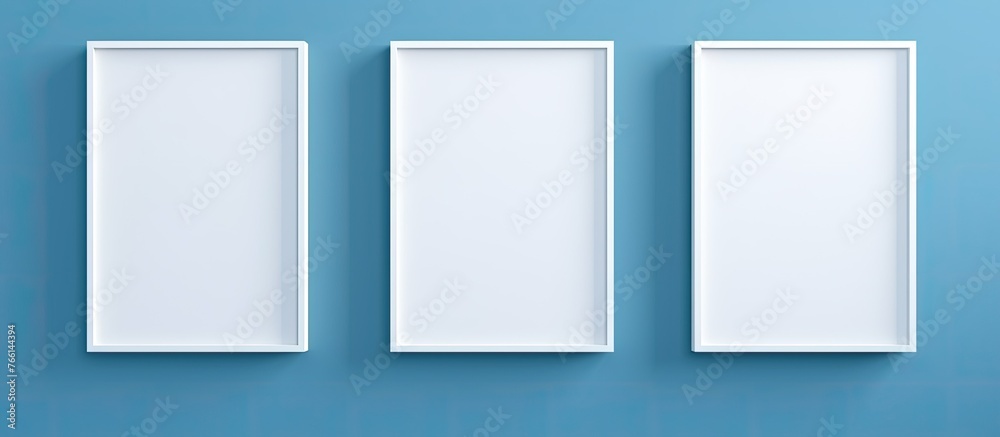 Three identical white picture frames are hanging neatly on a plain blue wall, creating a simple and modern display