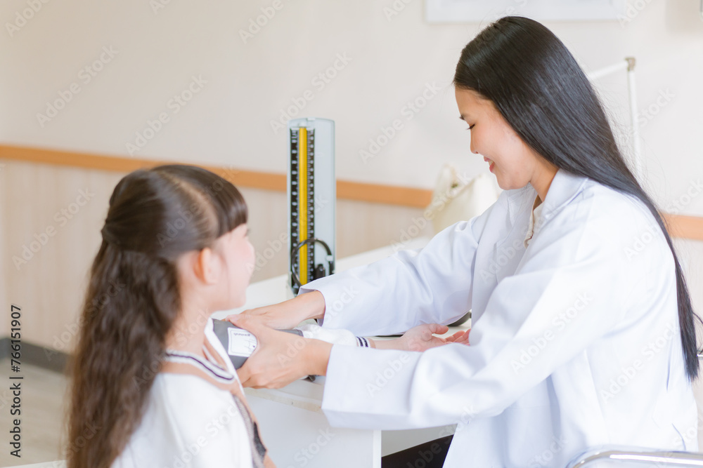 Doctor checking blood pressure to a patient. The doctor is inserting a device into the arm to measure blood pressure for a physical examination. Doctor checking blood pressure to a patient. The doctor is inserting a device into the arm to measure blood pressure for a physical examination.