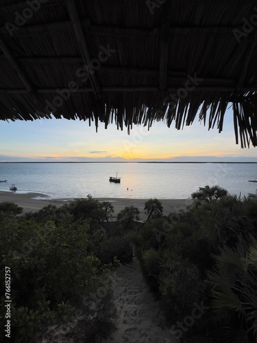 A view if the ocean from a thatched roof house in the tropics.