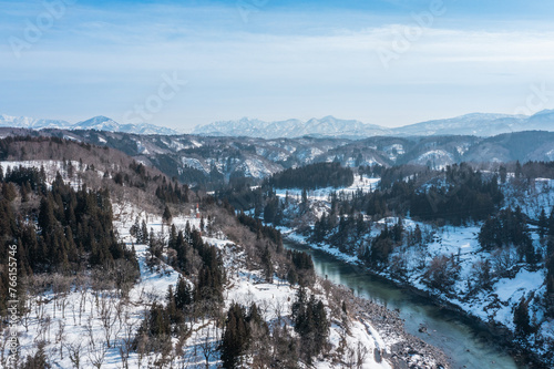 ドローン写真：晴れた日の美しい雪山と千曲川の風景