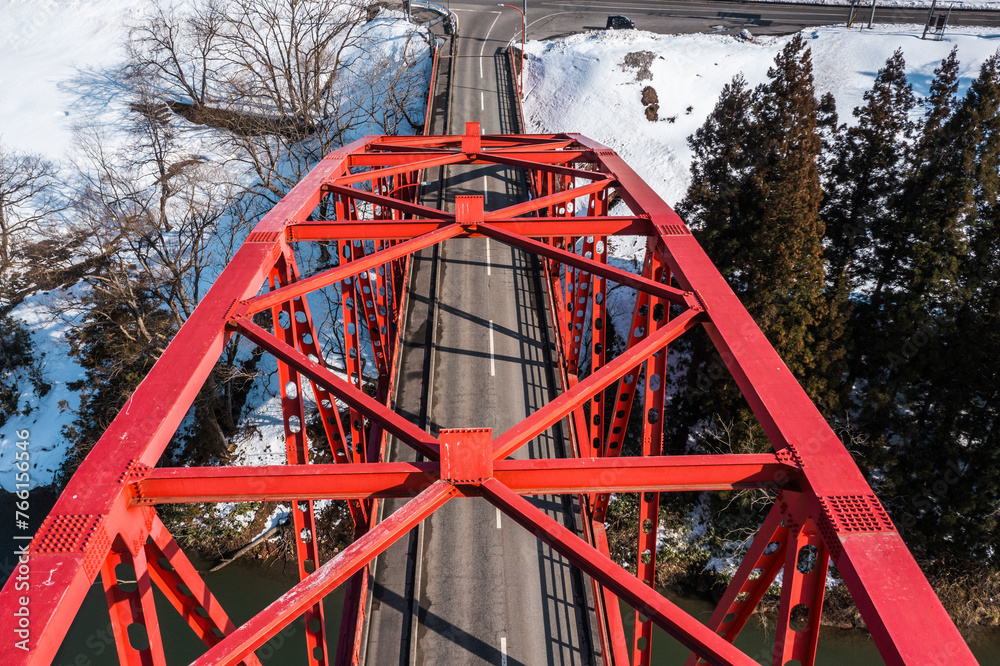 ドローン写真：トラス構造の赤い橋と、晴れた冬の自然