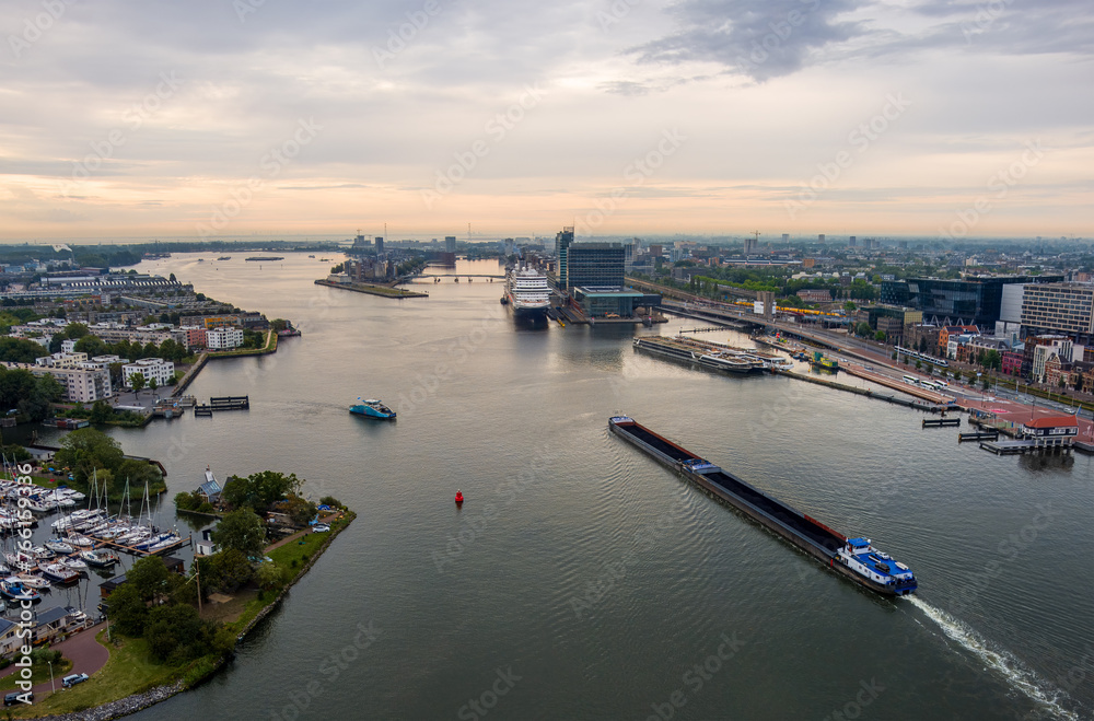 Amsterdam, Netherlands. A barge with coal floats on the water. Bay IJ. (Amsterdam). Panorama of the city on a summer morning in cloudy weather. Aerial view