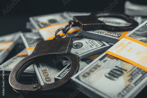 Close-up of handcuffs lying on top of dollars on a black background. Packs of dollars and handbrake boxes lie beautifully on a black background. Money fraud concept.