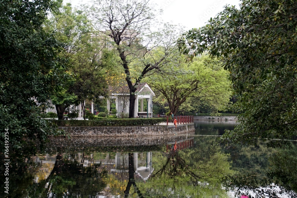 a house is reflected on the water of a lake with a gazebo