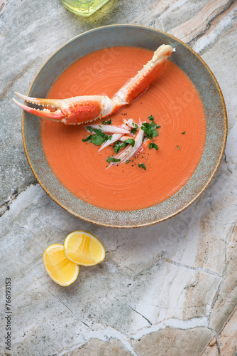 Plate of bisque with crab meat on a light-grey granite background, vertical shot with space, top view
