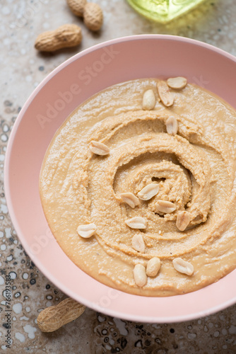 Roseate bowl with peanut butter or paste made from ground, dry-roasted peanuts, vertical shot, middle close-up
