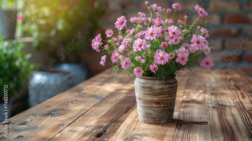  a vase filled with pink flowers sitting on top of a wooden table next to a potted plant on top of a wooden table.