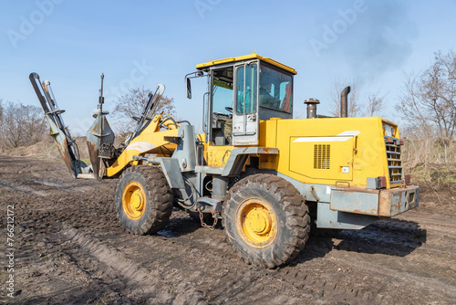 Male worker drives tree transplanter heavy machine. Landscaping, seasonal agricultural engineering, large trees landing machines. Specialized machine for transplanting and transport trees. photo